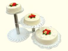 3-stöckige, gestaffelte Hochzeitstorte aus Buttercreme mit cremefarbenem Zuckerüberzug. Durch die dezente Gestaltung kommen die roten Blumenbuketts voll zur Geltung.