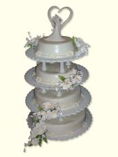 4-stöckige Hochzeitstorte aus Buttercreme mit Zuckerguss und sehr schönem Porzellanbrautpaar auf festlicher, weißer Kunststoffetagere.